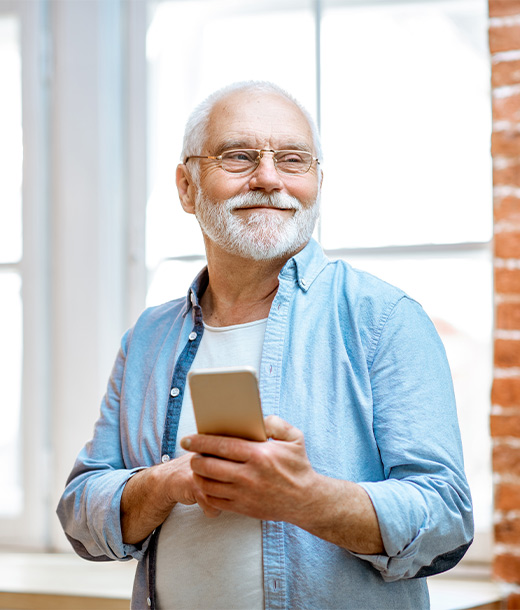 senior man smiling holding his cell phone contact investsafe financial crystal river fl